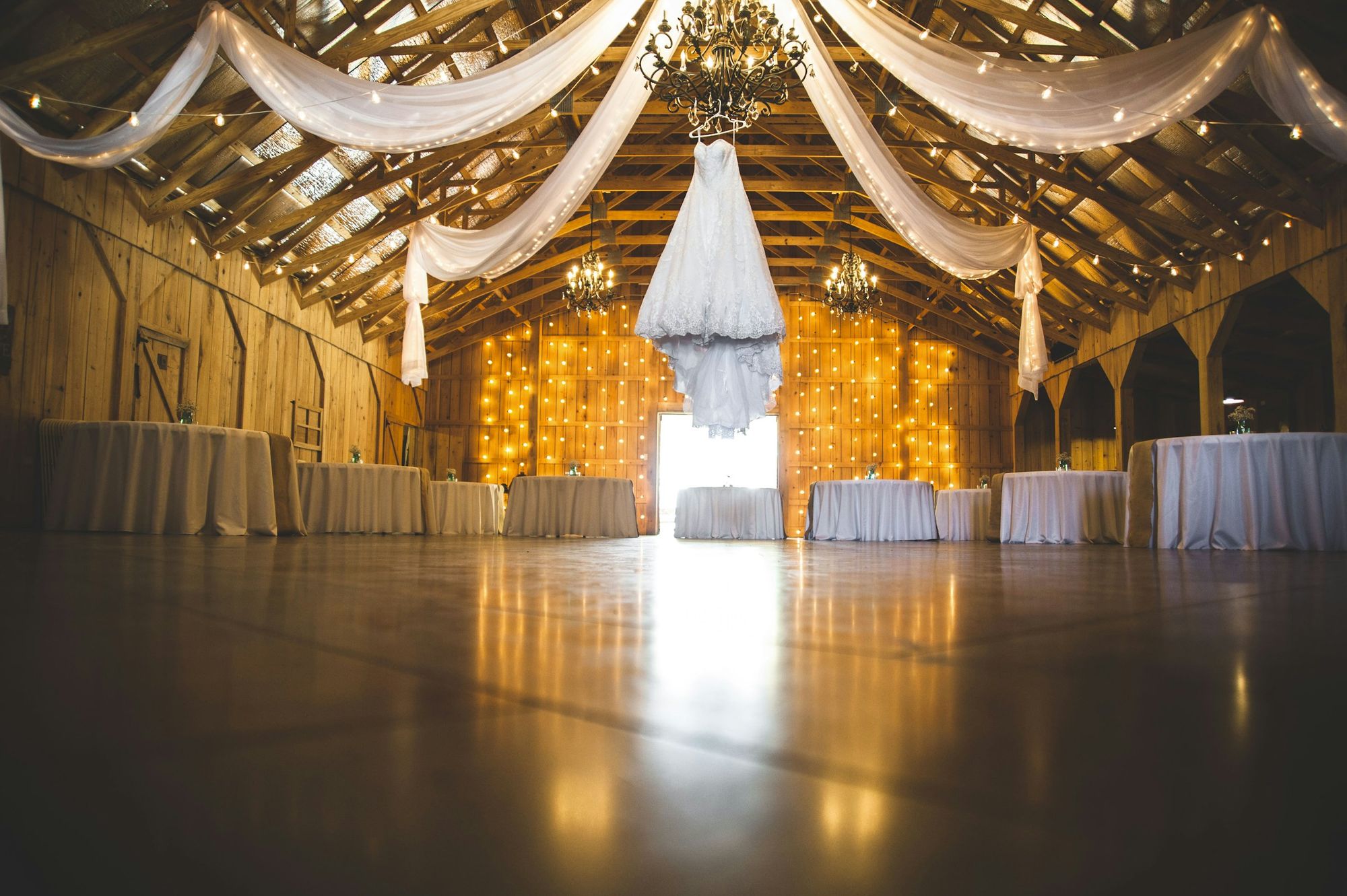 The Hall at dusk: a timber hall with draped ceilings, a chandelier and a glowing doorway