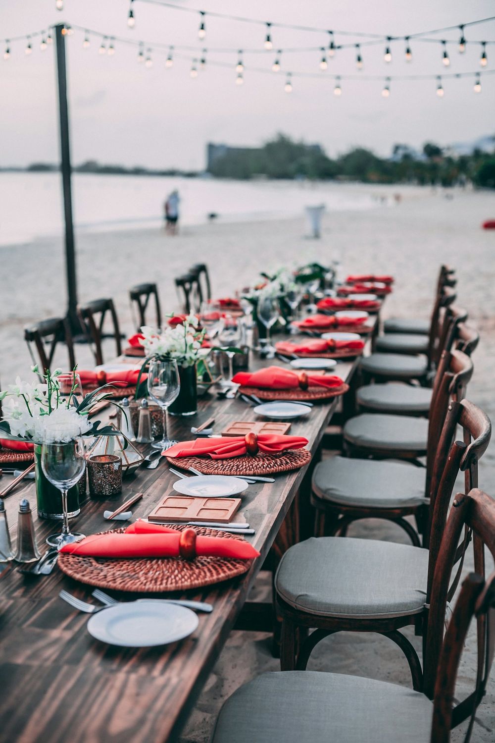 A long outdoor dinner table under string lights at dusk